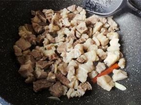 炒出片刻，牛腩微黄，放入桂皮，八角翻炒出香味，撒入点料酒继续翻炒。