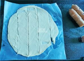 把手抓饼擀一擀，根据香肠段的长度，切成四个长条。