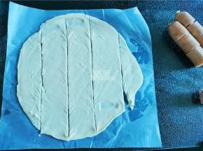把手抓饼擀一擀，根据香肠段的长度，切成四个长条。