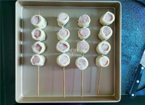 取一根竹签，串入四个香肠段，放入学厨的烤盘上等待烤制。