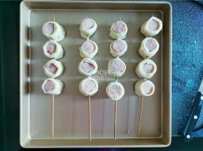 取一根竹签，串入四个香肠段，放入学厨的烤盘上等待烤制。