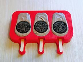 将雪糕液倒入模具中，轻轻震几下，将气泡震出，上面各摆放上一块饼干。