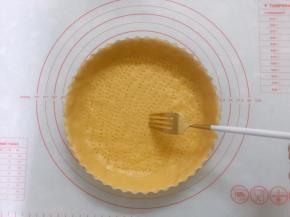 将派皮放入派盘内，四周用手按压与派盘贴合紧实，用擀面杖擀去多余的派皮，用餐叉在派皮底部插出一排排小孔