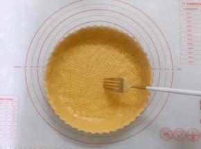 将派皮放入派盘内，四周用手按压与派盘贴合紧实，用擀面杖擀去多余的派皮，用餐叉在派皮底部插出一排排小孔