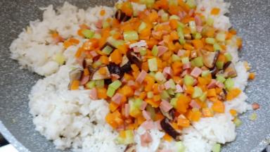 将米饭炒松散后加入胡萝卜等配料翻炒均匀。