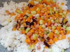 将米饭炒松散后加入胡萝卜等配料翻炒均匀。