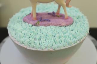 绿色的淡奶油装入已经装好小草裱花嘴的裱花袋内，在蛋糕胚上面挤好小草奶油，放上独角兽摆件。