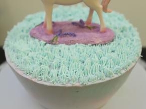 绿色的淡奶油装入已经装好小草裱花嘴的裱花袋内，在蛋糕胚上面挤好小草奶油，放上独角兽摆件。