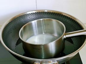 锅中加入60g牛奶，白砂糖隔水将糖融化。