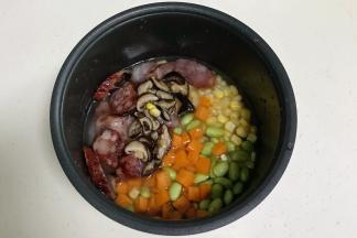 放入腊肠、香菇、胡萝卜、玉米粒和毛豆。