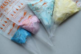 剩余的淡奶油分成4份，分别加入蓝、红、黄和紫色，调成四种颜色的奶油，装入裱花袋。