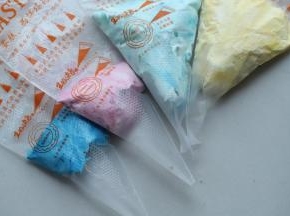 剩余的淡奶油分成4份，分别加入蓝、红、黄和紫色，调成四种颜色的奶油，装入裱花袋。