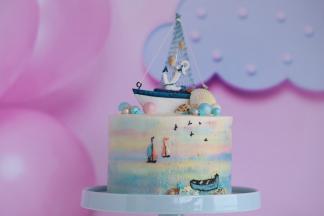 蛋糕上摆放好帆船模型，用糖珠和巧克力贝壳装饰。