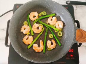 转最小火，把芦笋和虾仁铺在锅底，不要叠在一起。