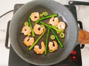 转最小火，把芦笋和虾仁铺在锅底，不要叠在一起。