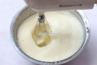 煮沸的牛奶缓慢呈细线状加入蛋黄中，同时用电动打蛋器高速搅打，打发至蛋黄液逐渐膨胀变白
