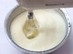 煮沸的牛奶缓慢呈细线状加入蛋黄中，同时用电动打蛋器高速搅打，打发至蛋黄液逐渐膨胀变白