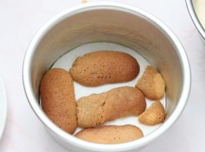 手指饼干在咖啡酒里面滚一圈，摆入6寸圆模底部，再倒入1/3的慕斯糊