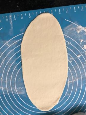 取一份面团擀成椭圆形，擀长一些。