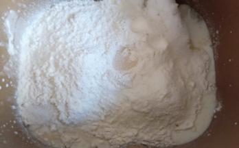 再放入全麦粉和高筋面粉，对角放盐和糖，中间挖个洞放入酵母。