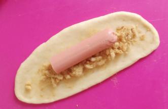 放入肉松和火腿肠，卷起来收口捏紧朝下。