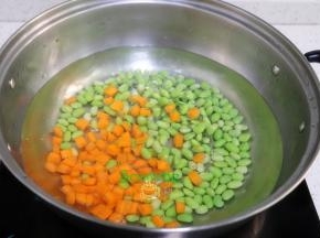 清水煮沸，把切好的胡萝卜粒，毛豆倒入锅里少许盐，汆烫熟，捞出，放凉。
