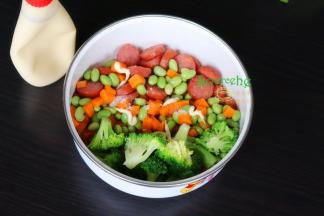 把煎好的牛肉肠、汆烫熟的胡萝卜粒、毛豆粒、西兰花，倒入一个大盘里，加沙拉酱拌均。