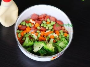 把煎好的牛肉肠、汆烫熟的胡萝卜粒、毛豆粒、西兰花，倒入一个大盘里，加沙拉酱拌均。
