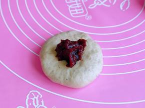 取一块面团，用擀面杖轻轻的擀圆，放入豆沙馅。