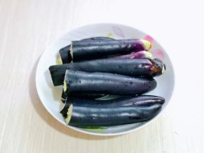 首先将茄子洗干净，掰开，放入盘中。
