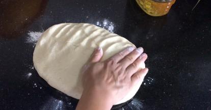 取出发酵好的面团，放入撒上干面粉的台面上，拍打排气