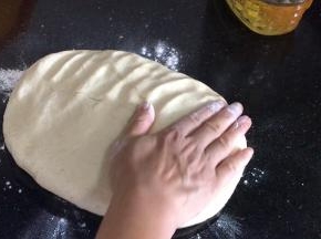 取出发酵好的面团，放入撒上干面粉的台面上，拍打排气