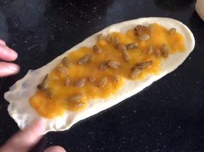 撒上葡萄干，把一头的边缘按成薄皮