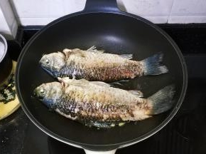 锅里热油放入姜丝爆香，再放入两条鲫鱼煎至两边金黄色