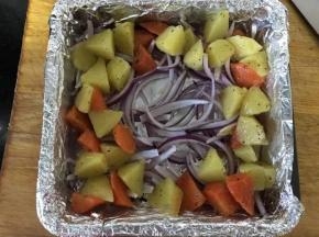 烤盘垫锡纸，放入洋葱丝 ，再放好土豆和胡萝卜，