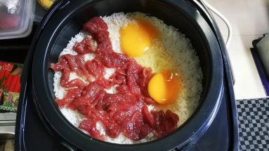 饭煮至起鱼眼时放入腌好的牛肉片，打入两个鸡蛋，盖上盖子继续煮至饭好