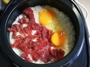 饭煮至起鱼眼时放入腌好的牛肉片，打入两个鸡蛋，盖上盖子继续煮至饭好