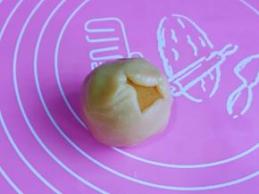 取一块月饼皮，用擀面杖擀薄，再放上奶黄馅，虎口手法包起来。收口捏紧。