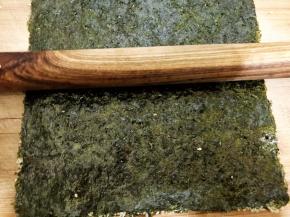 再取一张海苔在粗糙面刷上酱汁后，跟有芝麻的海苔重合在一起，用擀面杖擀压让两片海苔贴合更紧