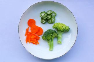 胡萝卜切一个圆形和长短不一的细条做太阳，西兰花对半切开，做成大树状，秋葵切小圈做小花。