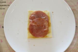 取出烤好的吐司片，放上火腿肠片。