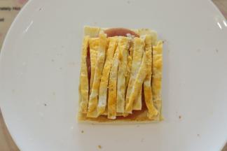 鸡蛋切成细条，放在火腿肠片上。