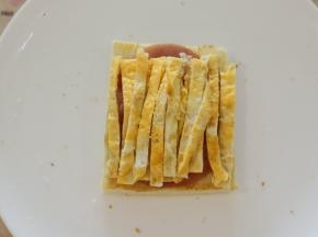 鸡蛋切成细条，放在火腿肠片上。