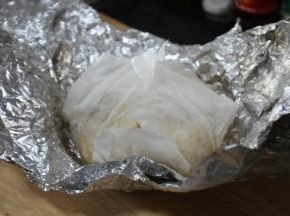 将腌制好的童子鸡先用厨房料理纸（油纸）裹好，再用铝箔纸裹上，我裹了2层铝箔纸，这样更严实些。
裹一层油纸是避免童子鸡在炸时候流出的汁水和铝箔纸粘在一起，破坏童子鸡的品相。