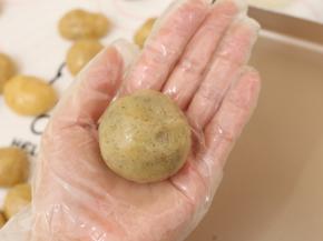 取出一个月饼皮剂子，包入一颗馅料，最后收口要收紧，并将其滚圆。