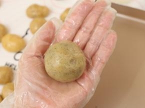 取出一个月饼皮剂子，包入一颗馅料，最后收口要收紧，并将其滚圆。