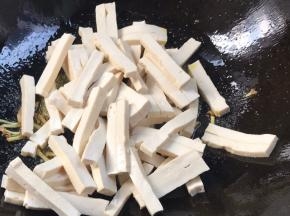 加入香干，煎至表面焦黄