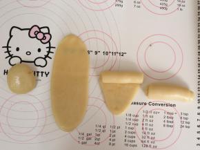 包好的水油皮收口朝上，用擀面杖从中间往上和往下擀开，由上往下卷起来，这样就完成了第一次擀卷。