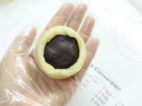 翻过来，将皮收一下，让它紧贴着馅料。一手大拇指按住馅料，另一手虎口往上推饼皮，使它紧贴着馅料并慢慢地往上爬，最后收口，收口一定要收紧。