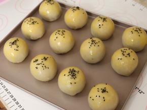 全部处理好的面团放在烤盘上，刷上一层蛋黄液，撒上黑芝麻。